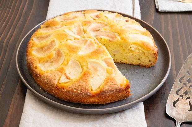 Whole Italian pear cake, with a wedge on a plate