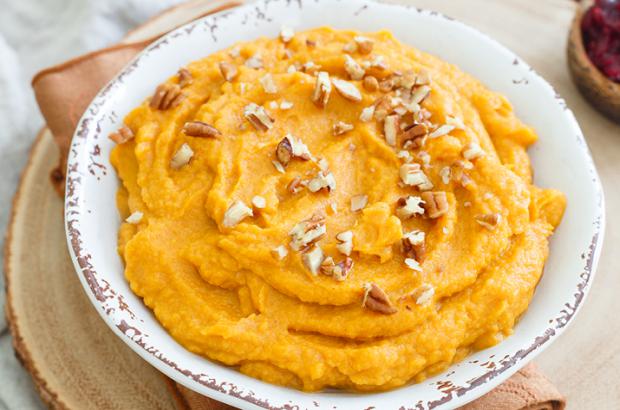 Bowl of mashed sweet potatoes topped with chopped pecans