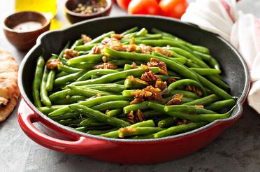 Sauteed green beans in a skillet with candied pecans