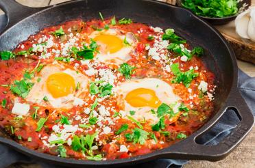 Shakshuka with spinach in a cast iron pan