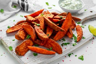 Spicy Sweet Potato Wedges on a Cutting Board with Jalapeno Sour Cream