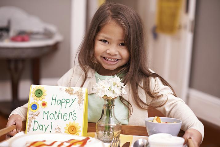 Child holding tray of food and card for Mother's Day