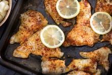 Cooked, spiced catfish fillets on a baking tray